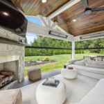 Covered porch with furniture, TV, Table and Chairs, and fireplace