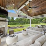 Covered porch with furniture, TV, Table and Chairs, and fireplace